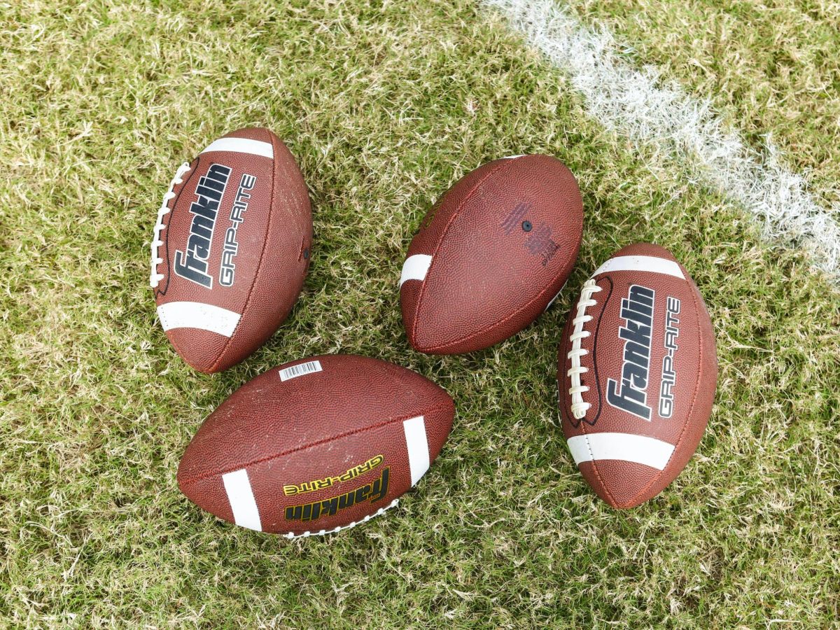 Image of four footballs on a field. Photo by Mick Haupt on Unsplash
  